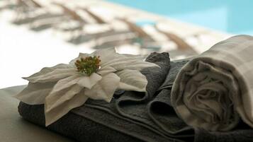 Una toalla doblada con una flor decorativa en una zona junto a la piscina.