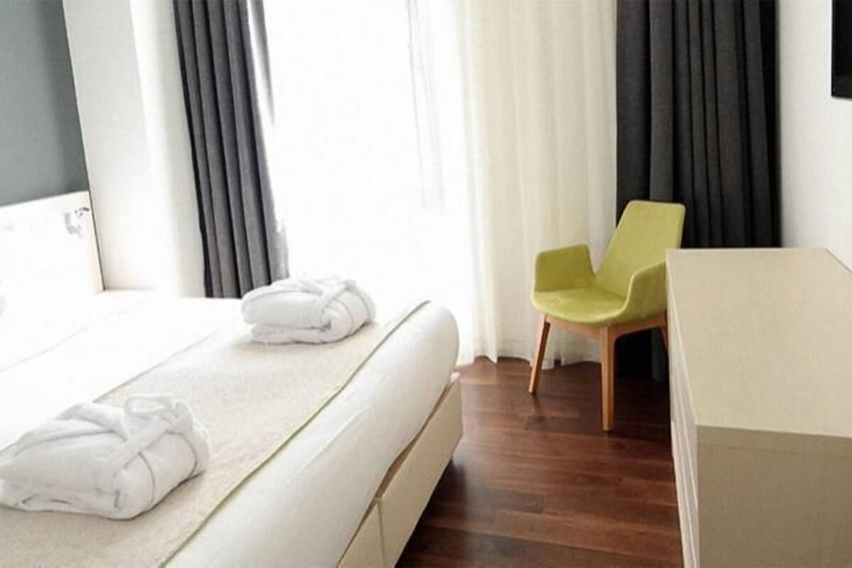 A hotel room with a bed, a chair, a desk, and a TV.