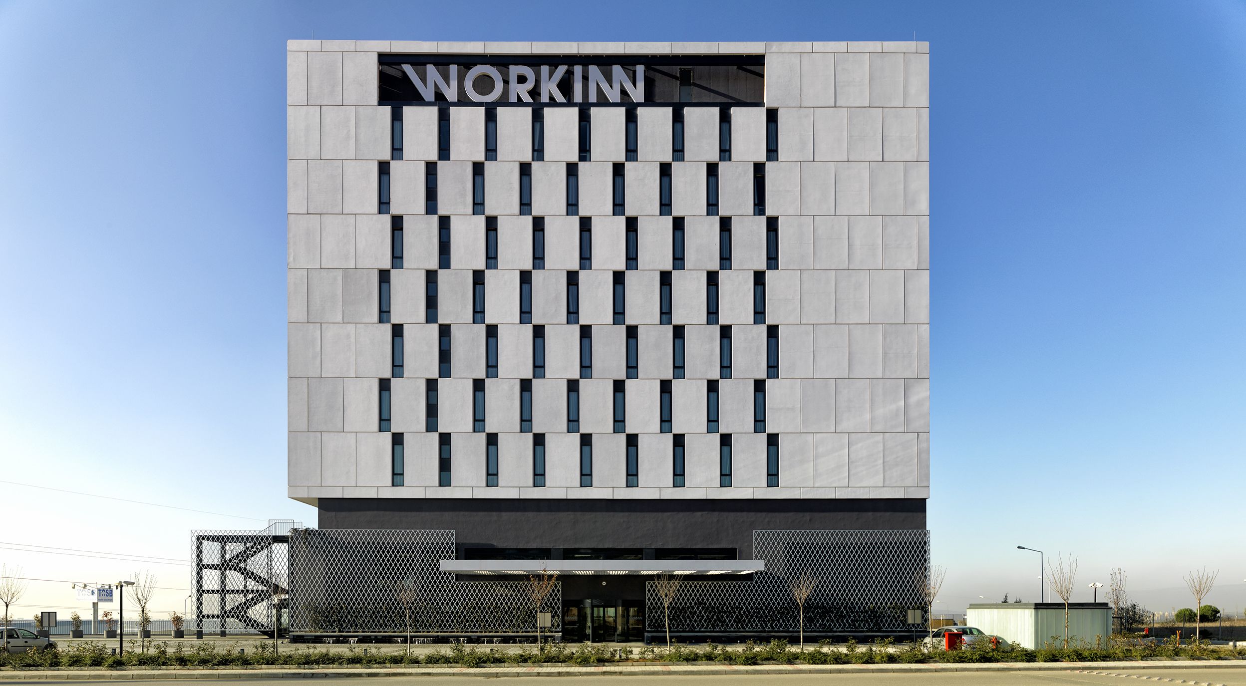Een modern gebouw met een gevel in rastervorm en de tekst 'WORKIN' duidelijk zichtbaar aan de bovenkant.