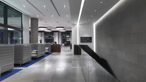 Un vestíbulo moderno con mostrador de recepción, zona de estar y escalera.