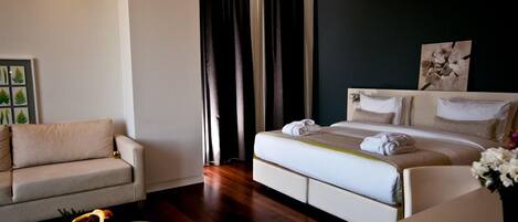 Una habitación de hotel moderna con una cama, un sofá y una mesa de centro con una botella y un vaso.