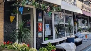 Un restaurante frente al mar con terraza, plantas en macetas y un letrero que dice 'frente al mar'.