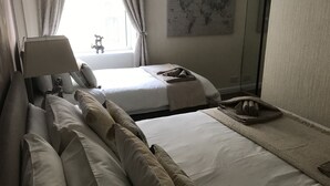 Een hotelkamer met twee bedden, een kaart aan de muur, een raam met gordijnen en een lamp.