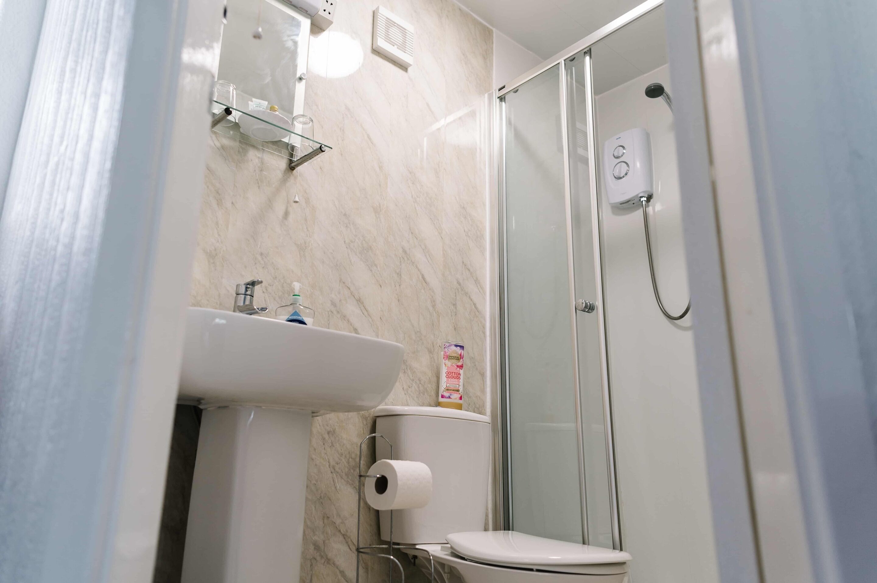 A bathroom with a toilet, sink, and glass shower enclosure.