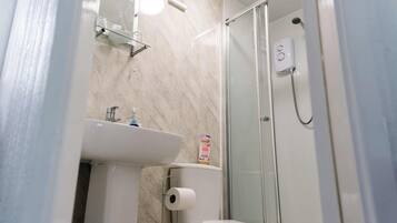 A bathroom with a toilet, sink, and glass shower enclosure.