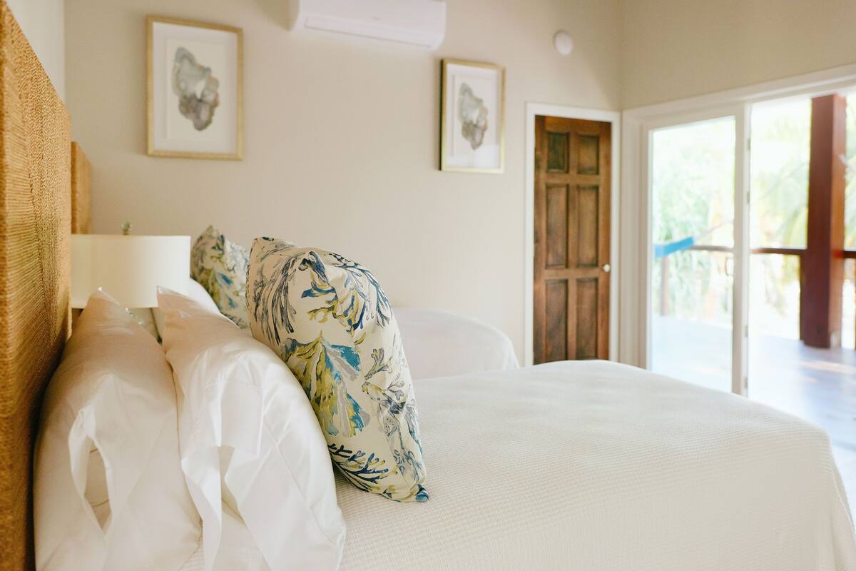 A bedroom with a large bed, white bedding, and two framed artworks on the wall.