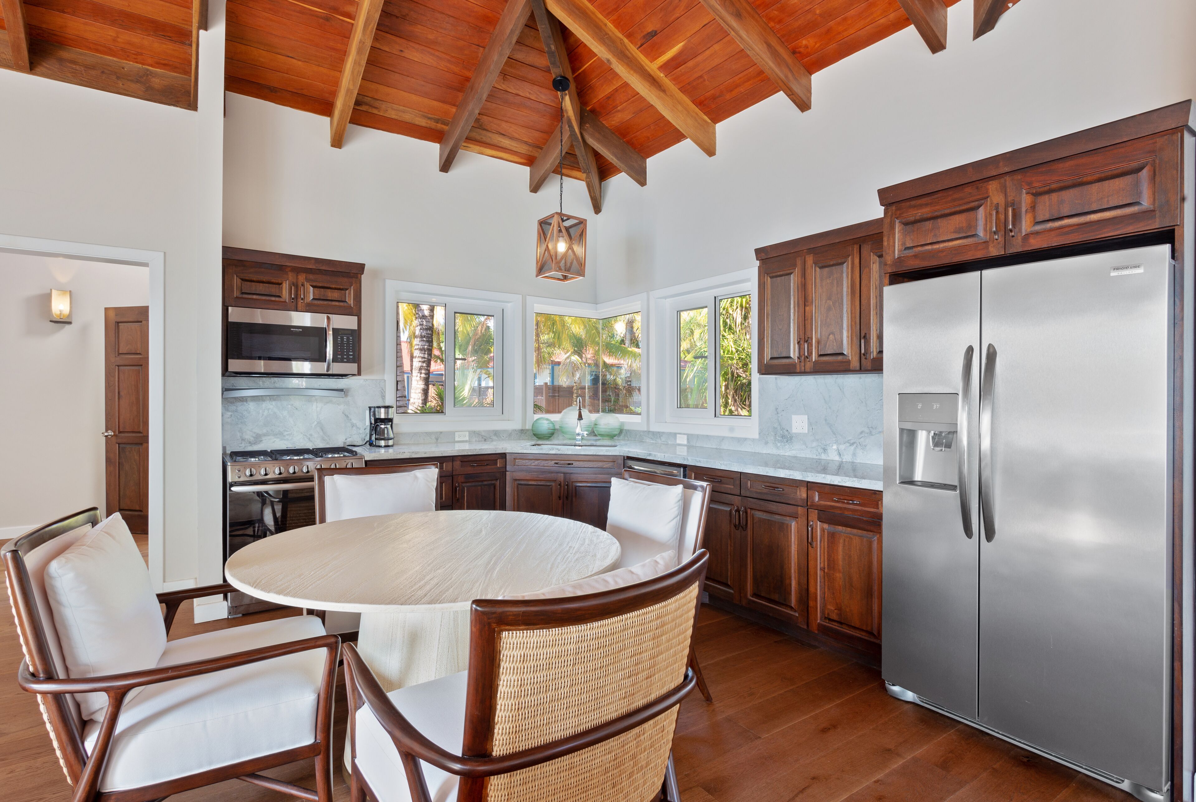A spacious kitchen with wooden cabinets, a stainless steel refrigerator, and a round dining table with wicker chairs.