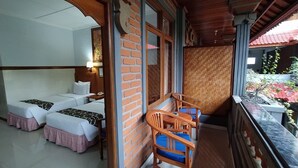 A hotel room with two beds, a wooden table with chairs, a balcony with a view of the outside. - Hotel Sorga (Kuta)