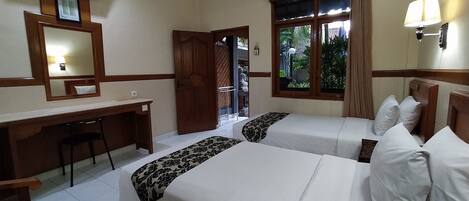 A hotel room with two beds, a desk, a chair, a TV, and a window with curtains.