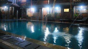A swimming pool with a tiled edge, surrounded by a building with multiple balconies and a brick facade. - Hotel Sorga (Kuta)