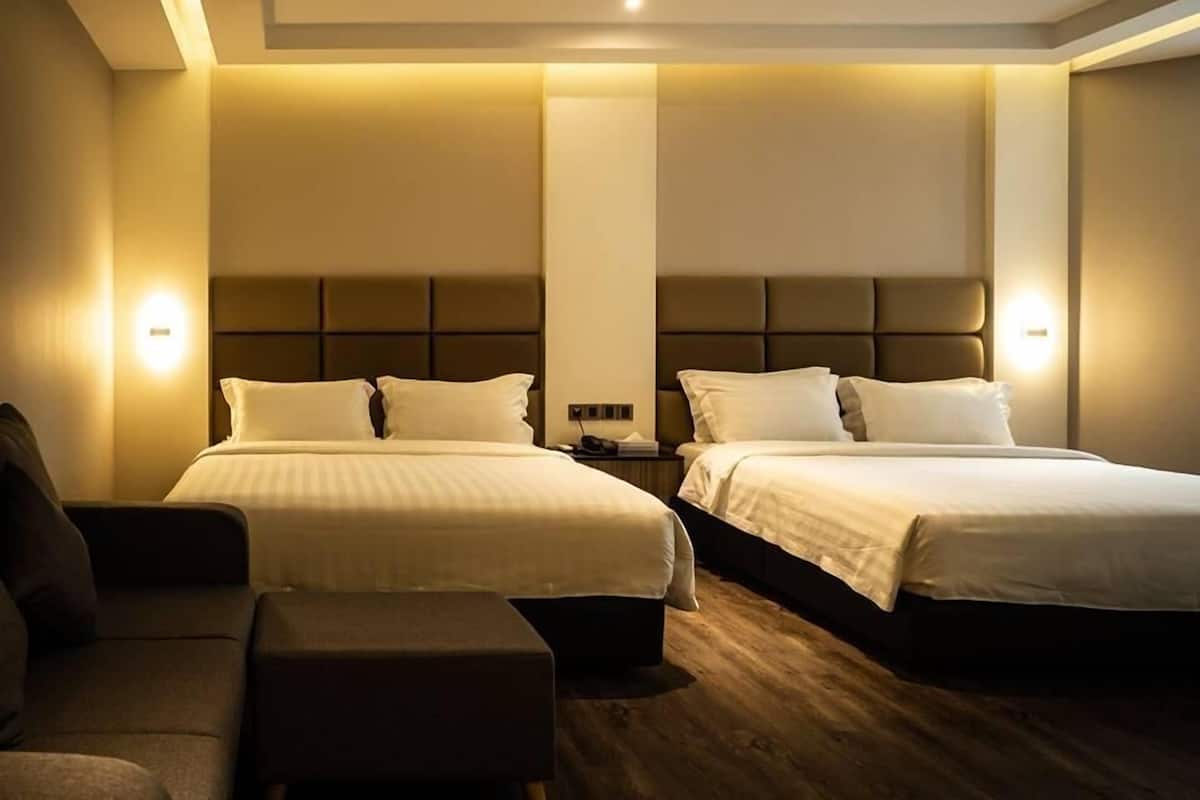 Ein Hotelzimmer mit zwei Betten, einem Schlafsofa und einem Nachttisch.