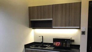 A modern kitchen with a black countertop, stainless steel appliances, and wooden cabinets. - KK Times Square Hotel (Kota Kinabalu)