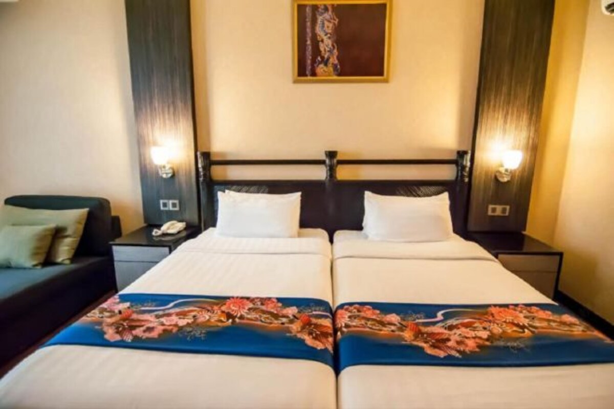 Ett hotellrum med två sängar, en soffa och ett nattduksbord med en telefon.