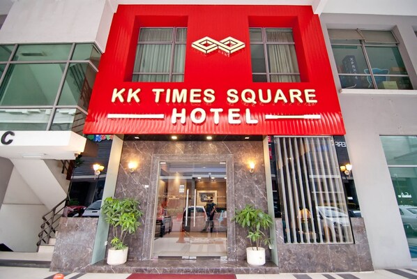 El exterior del Hotel KK Times Square, con una fachada roja llamativa y una amplia entrada de vidrio.