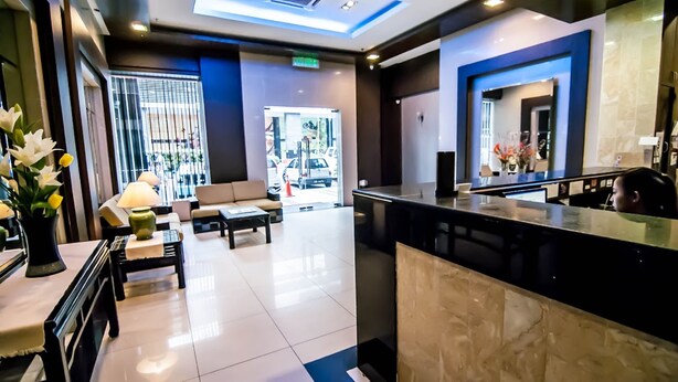 A modern hotel lobby with a reception desk, seating area, and a large window providing a view of the street. - KK Times Square Hotel (Kota Kinabalu)