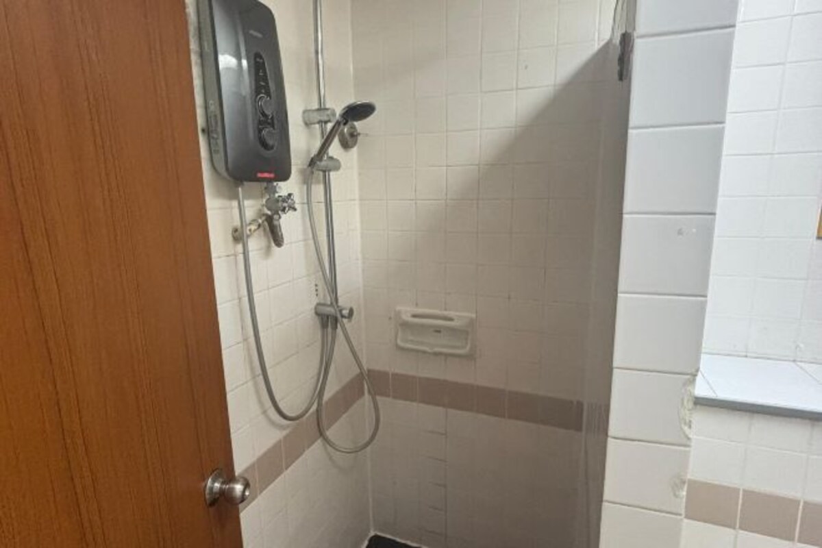 Une salle de bain avec une douche, un distributeur de savon et une porte.