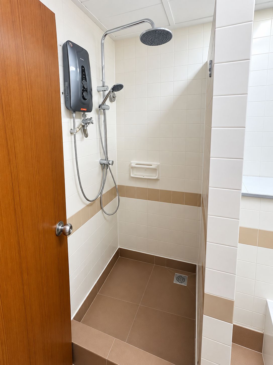A bathroom with a shower, a soap dispenser, and a toilet.