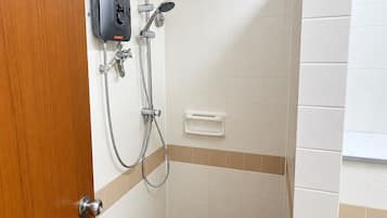 A bathroom with a shower, a soap dispenser, and a toilet.