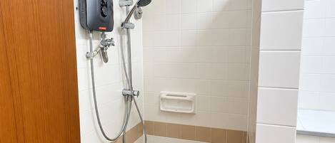 A bathroom with a shower, a soap dispenser, and a toilet.