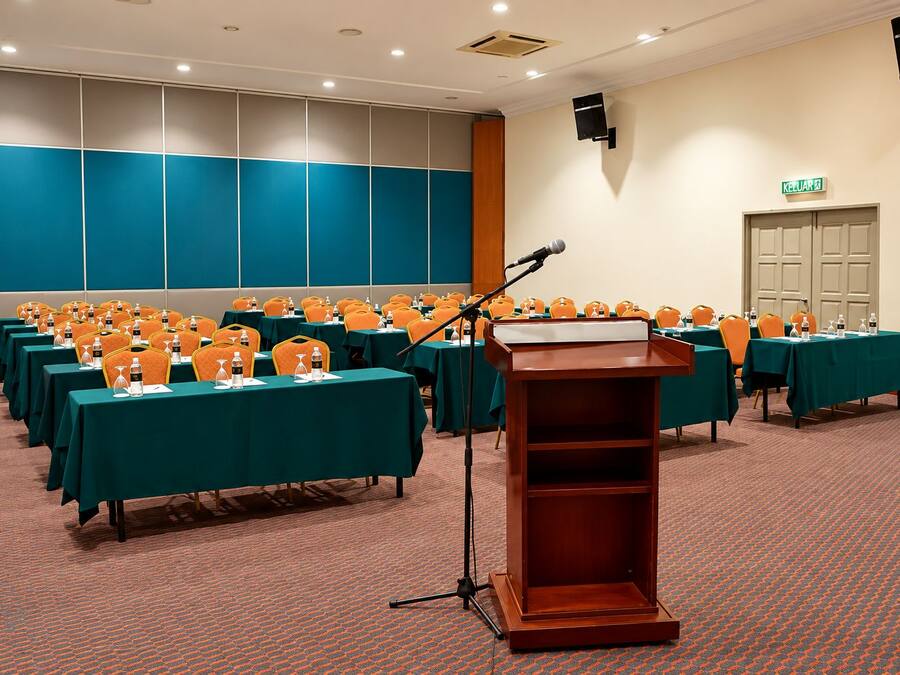 Une salle de conférence avec des rangées de tables, des chaises et un pupitre pour les présentations.