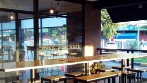 A modern restaurant interior with a long counter, multiple tables, and a view of the street outside. - Hotel Seri Malaysia Alor Setar (Alor Setar)