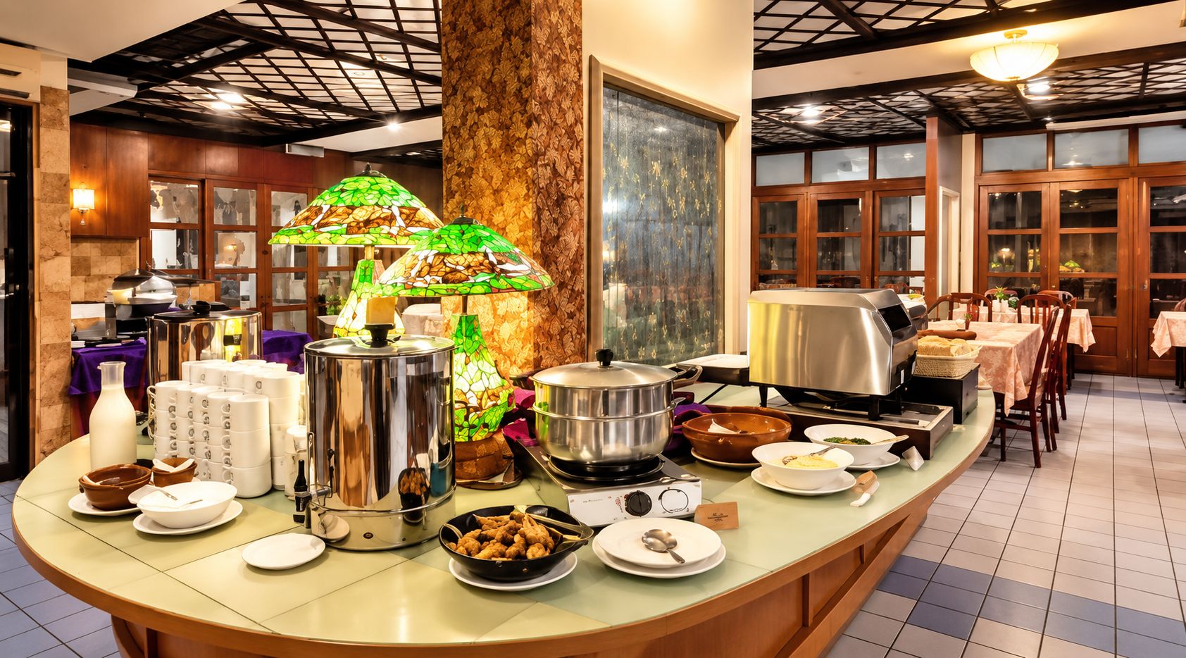 A buffet setup with various food items, a decorative lamp, and a large window.