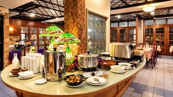 A buffet setup with various food items, a decorative lamp, and a large window.