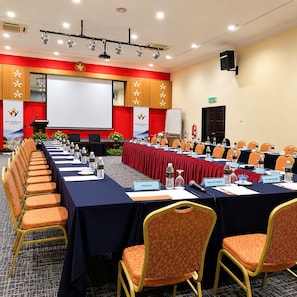 Un salón de conferencias con una mesa larga, sillas, tarjetas de identificación y una pantalla para proyector.