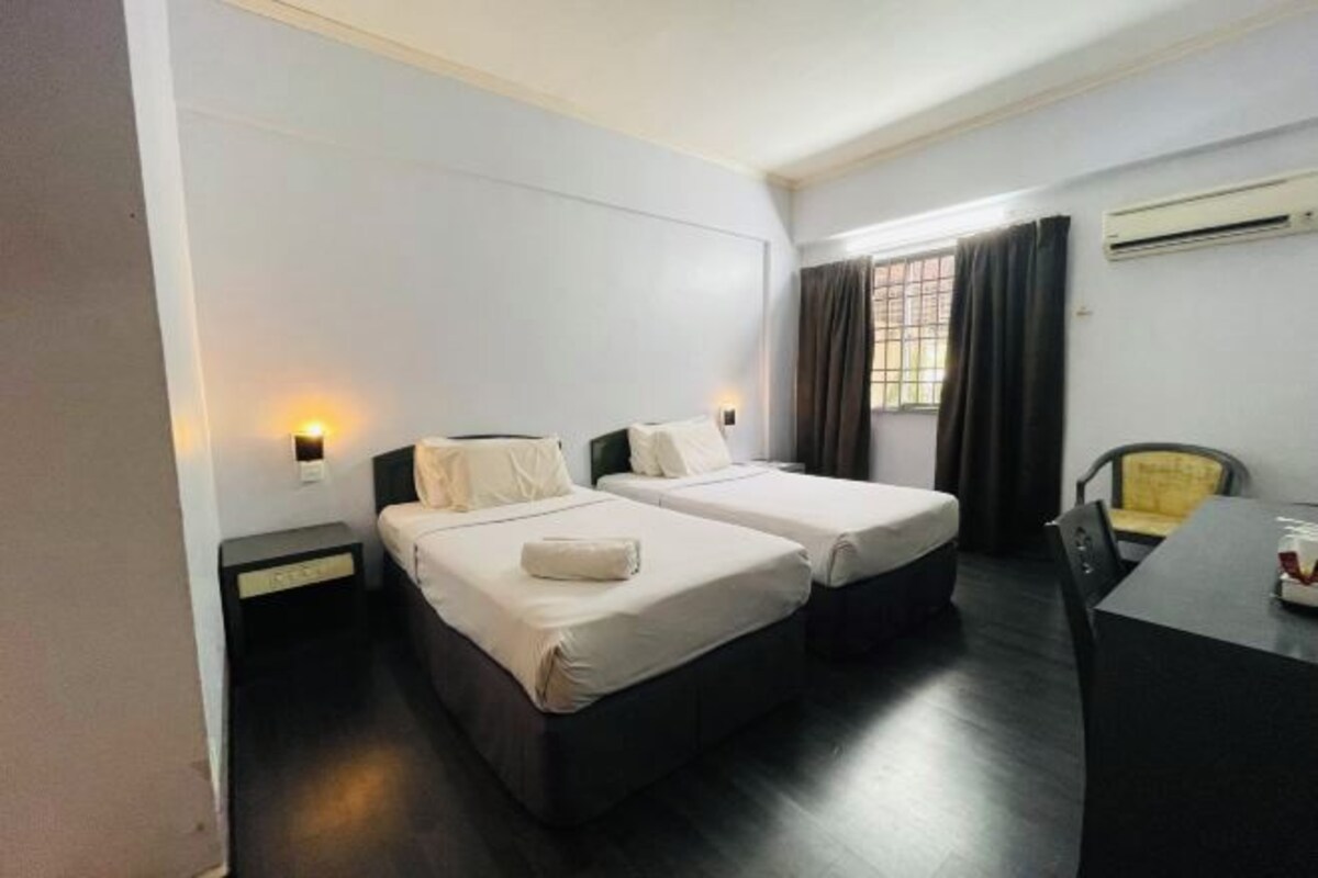Une chambre d’hôtel avec deux lits, un bureau et une chaise.