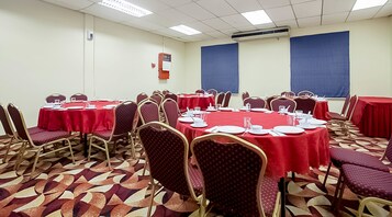 Un salón de conferencias con mesas redondas, manteles rojos y sillas a juego.
