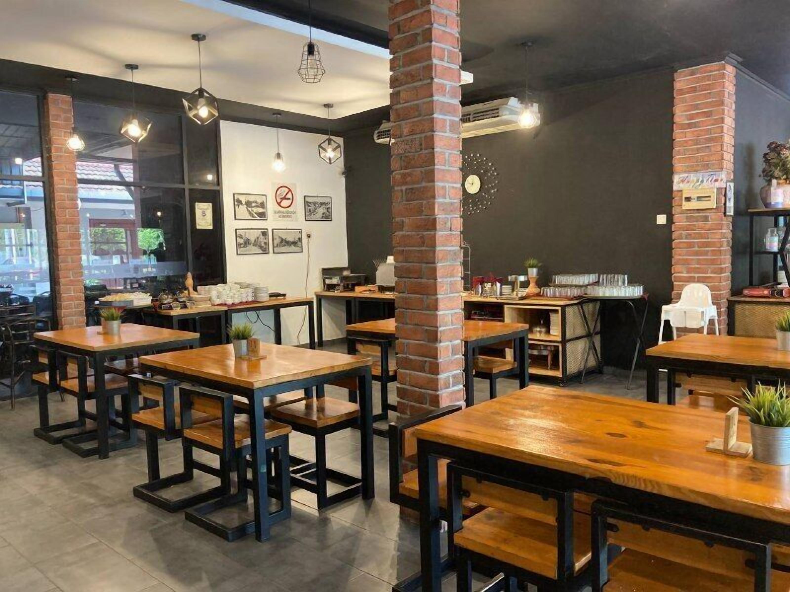 A restaurant interior with brick pillars, wooden tables, and hanging pendant lights.