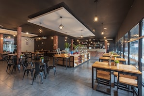 A modern cafe with wooden tables and chairs, a brick wall, and a large window.