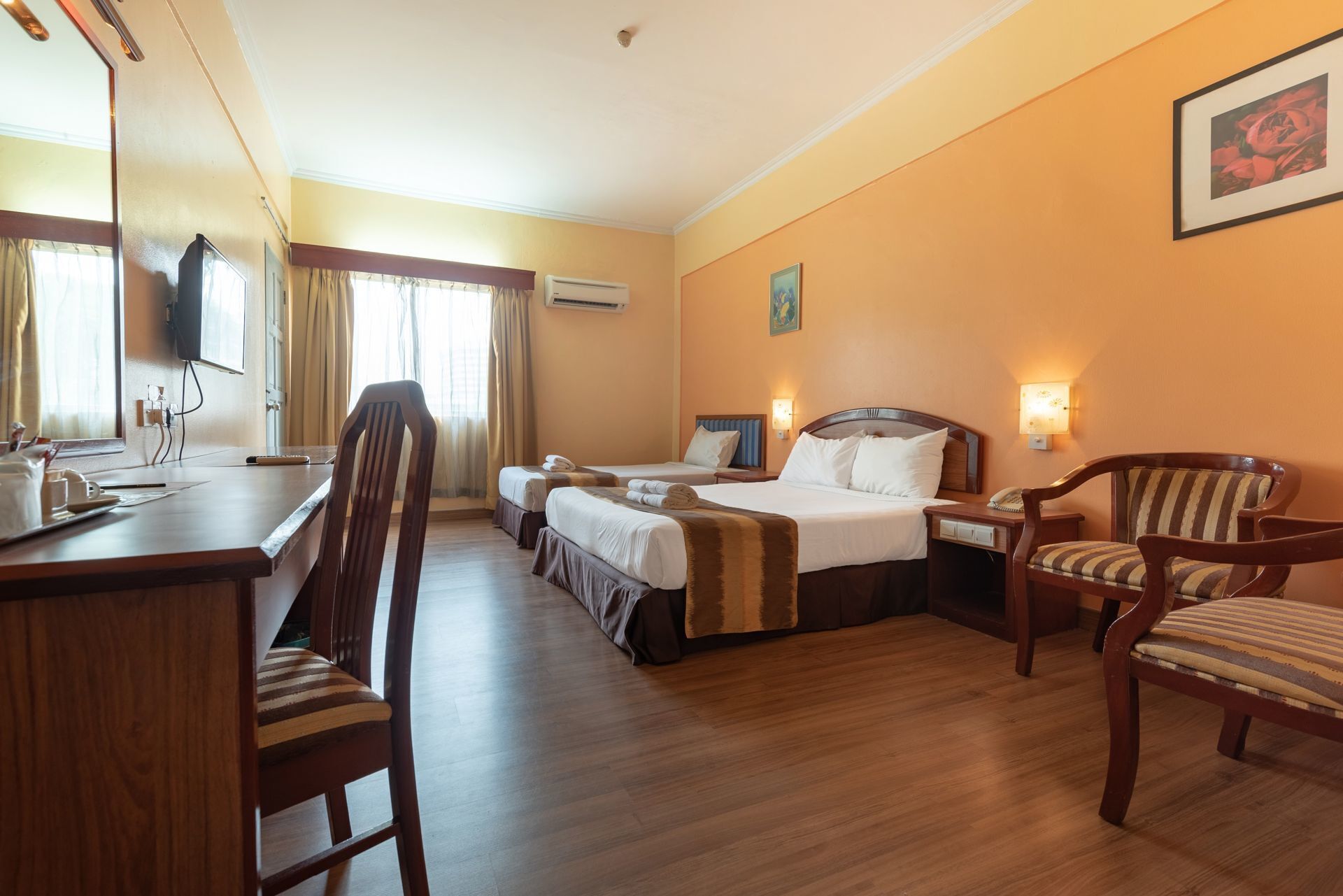 A hotel room with two beds, a desk, a chair, and a television.