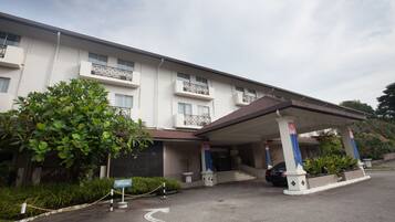 A hotel entrance with a covered parking area, a sign indicating VIP parking, and a building with multiple balconies.