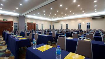 A conference room with rows of tables, chairs, and water bottles.