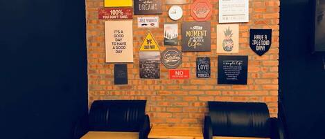 Un mur orné de divers affiches et panneaux d’inspiration, deux canapés en cuir noir et une table en bois.