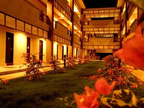 Un hôtel à plusieurs étages doté d’une cour intérieure agrémentée d’une pelouse bien entretenue et de plantes en fleurs.
