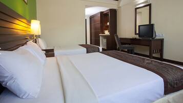A hotel room with two beds, a desk with a television, a chair, and a wardrobe.
