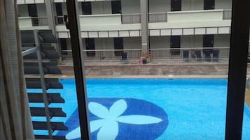 Une piscine aux motifs bleus et blancs, entourée d’un bâtiment doté de balcons et d’une clôture.