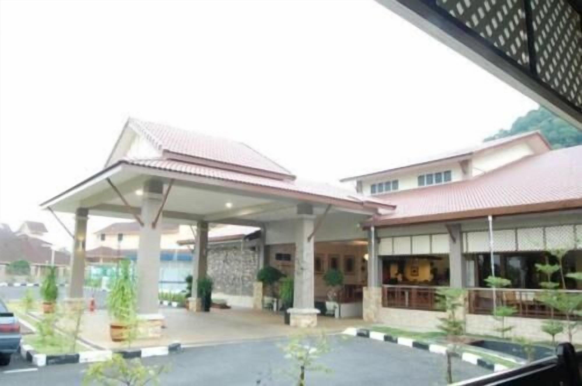 A building with a covered entrance, a parking lot, and a few potted plants.
