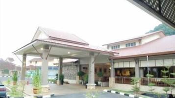 A building with a covered entrance, a parking lot, and a few potted plants.