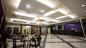 Un vestíbulo de hotel con mostrador de recepción, zona de estar y mostrador de entrada.