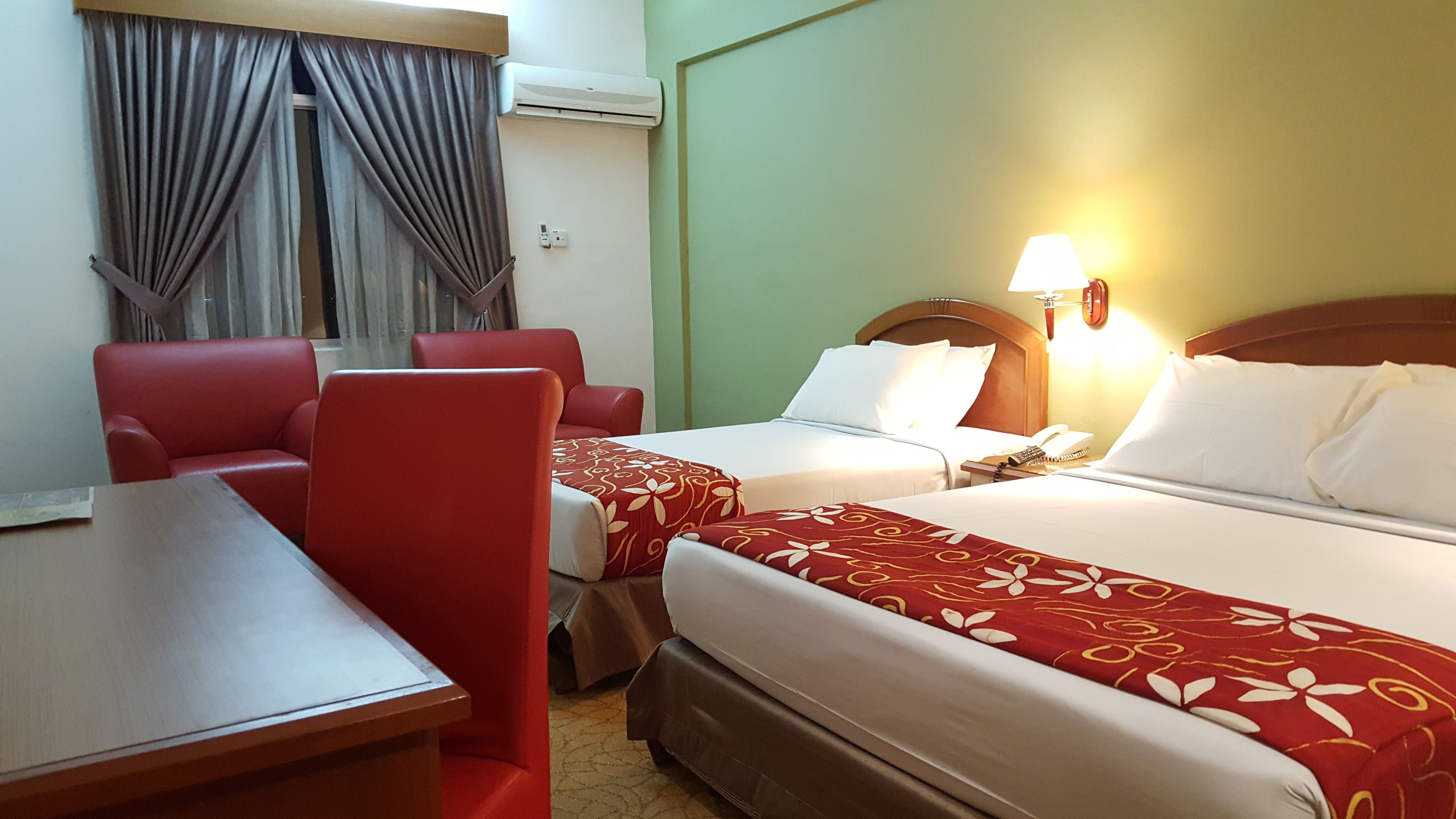 Habitación de hotel con dos camas, un escritorio, una silla y una lámpara.