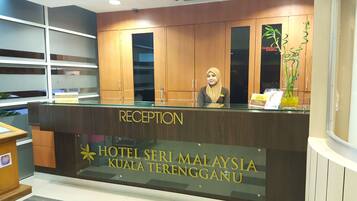 Bancada de recepção do Hotel Seri Malaysia Kuala Terengganu, com acabamento em madeira e tampo de vidro.