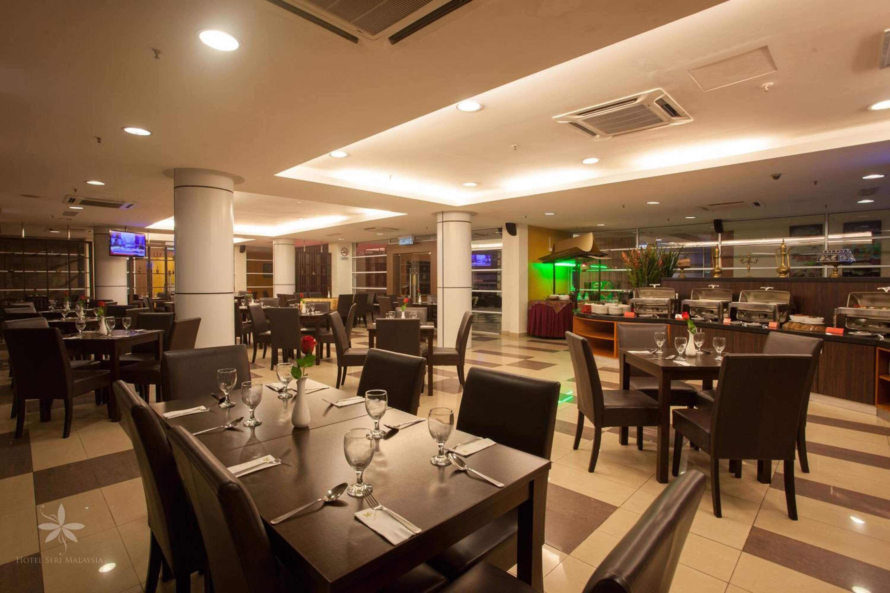 Un restaurante espacioso con varias mesas y sillas, una zona de bufé y una pantalla de televisión que muestra un programa.