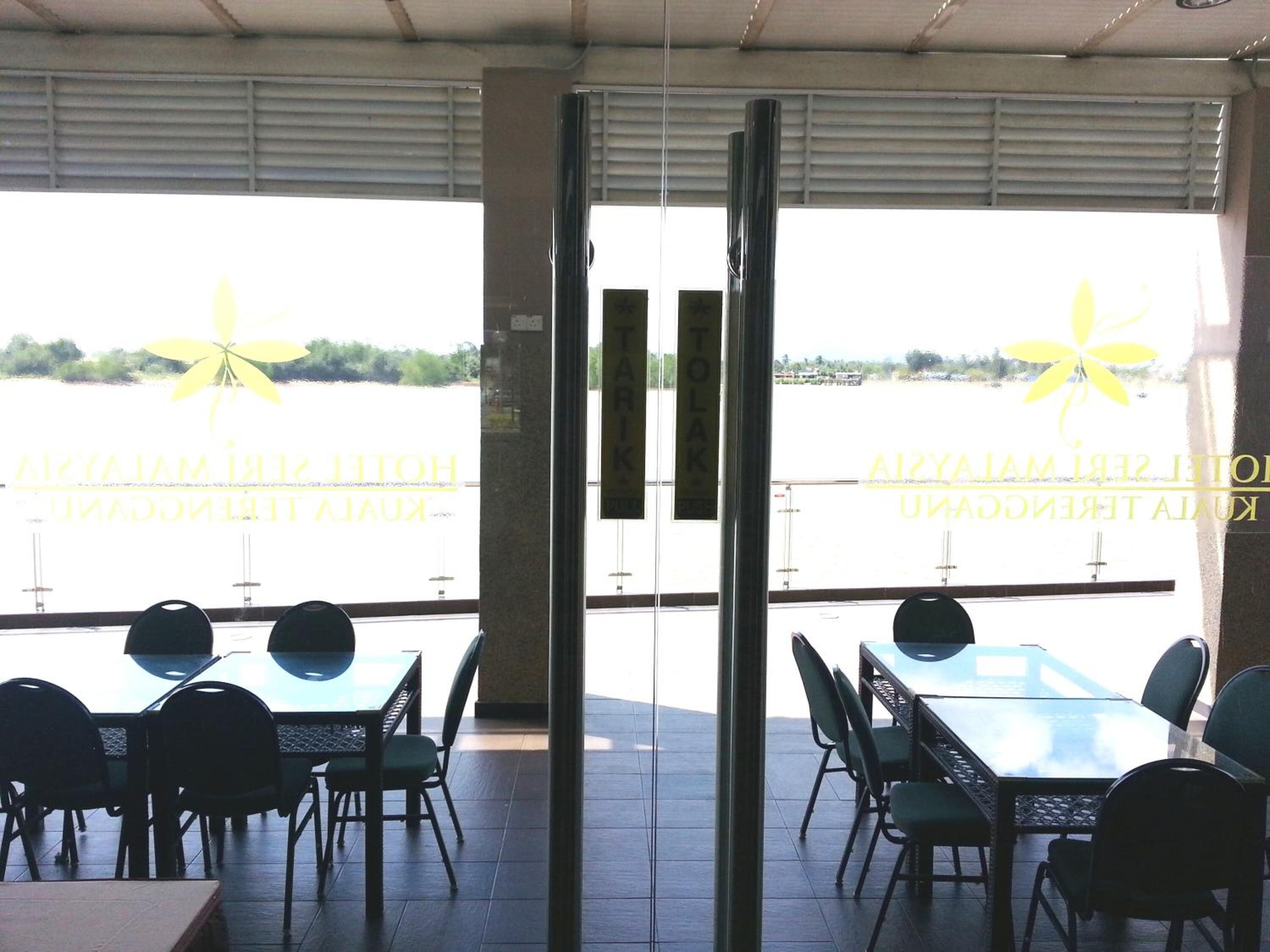 A restaurant with outdoor seating overlooking a body of water, featuring a logo and text on the glass doors.