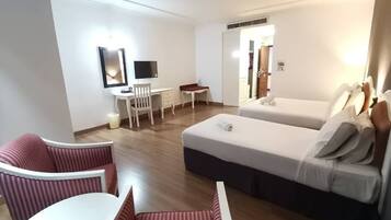 Una habitación de hotel con una cama, un escritorio, una silla y una mesita.