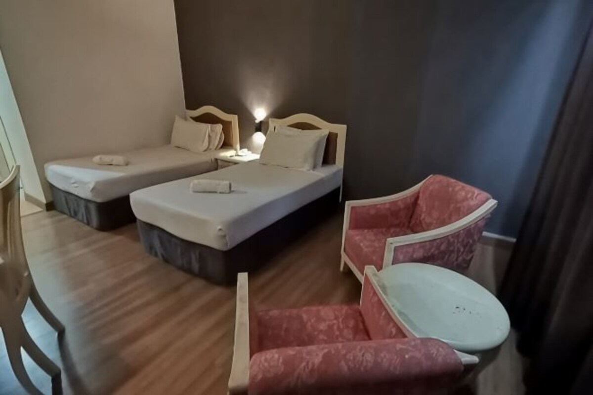 A room with two beds, a small table, and a sofa.