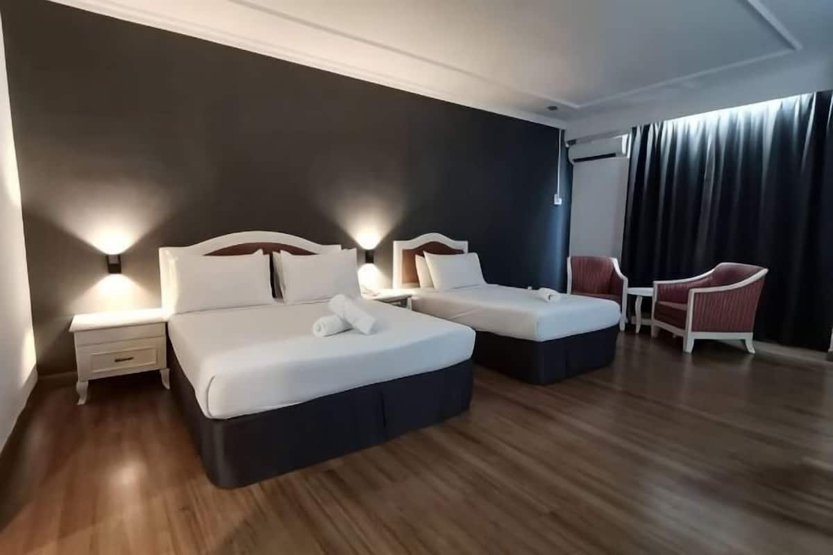 Habitación de hotel con dos camas, una mesita, dos sillas y una ventana con cortinas.