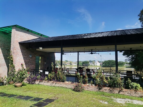 A covered outdoor seating area with a view of a river and buildings in the distance.